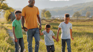 A single father enjoys an outdoor walk with his three children, sharing happy moments while holding hands and laughing.