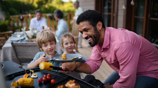 Multi generation family having party outside in the backyard on a patio.
