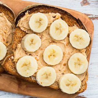 Healthy Snack Alternative made from Toasts from Wholewheat Bread with Peanut Butter and Banana with Cinnamon, Light Background